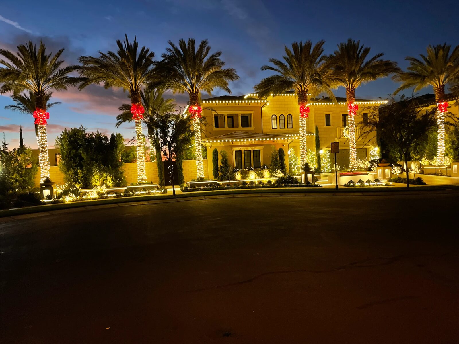 Mediterranean home with palms wrapped in lights and red bows